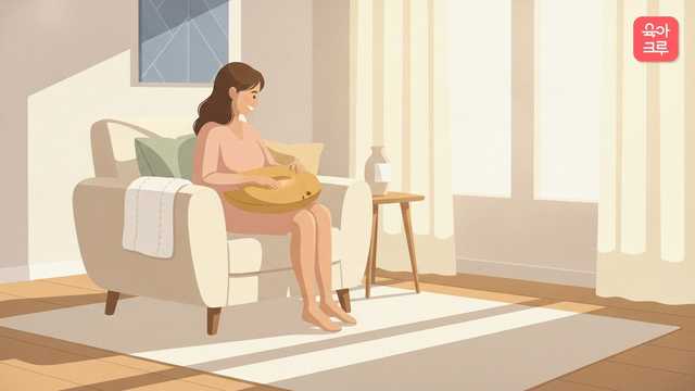 산모가 밝은 방 소파에 앉아 수유 쿠션을 정리하는 모습