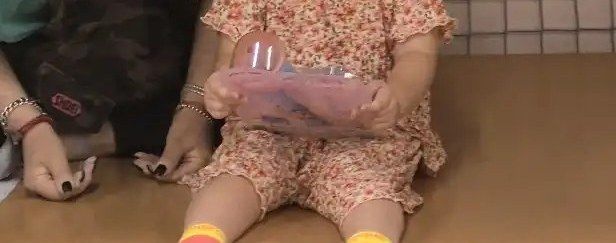 어른 곁에 앉아 장난감을 들여다보는 아이