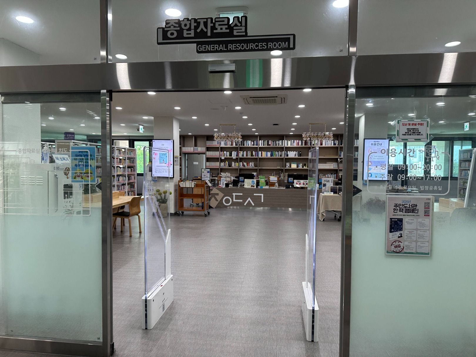 인천광역시교육청주안도서관 책들이 가득한 서가와 안내 데스크가 보이는 도서관 종합자료실 내부