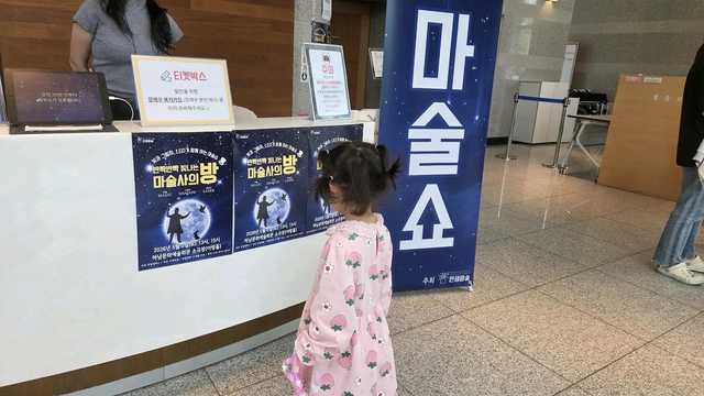 마술쇼 안내판 앞에 선 아이