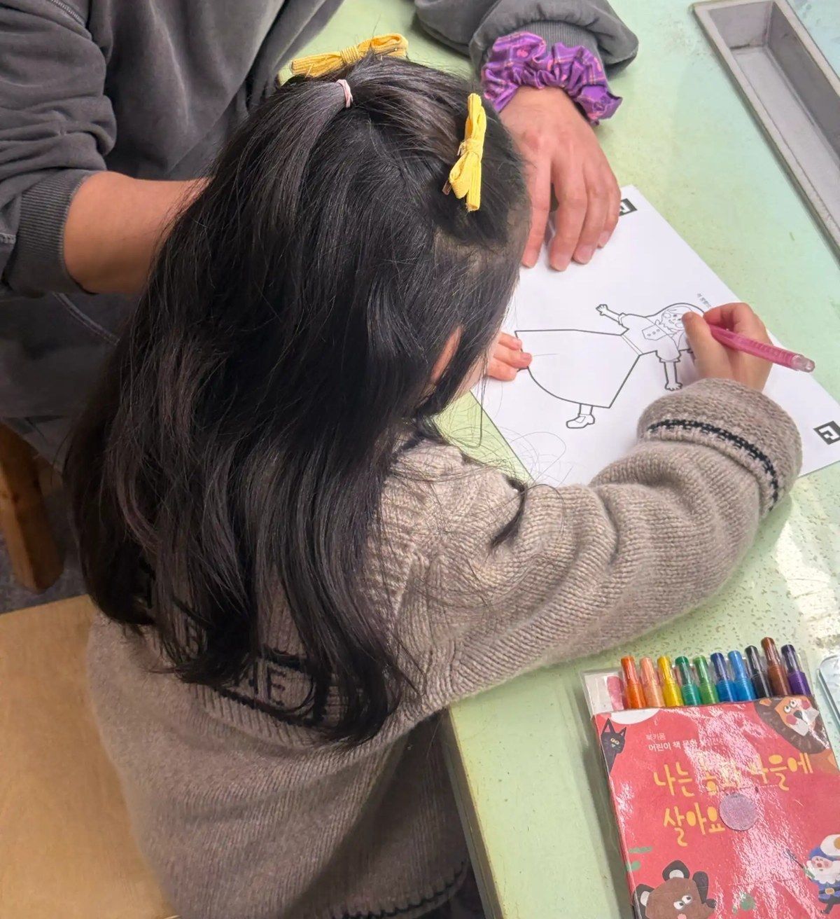 부모 곁에 나란히 앉아 그림을 그리는 아이