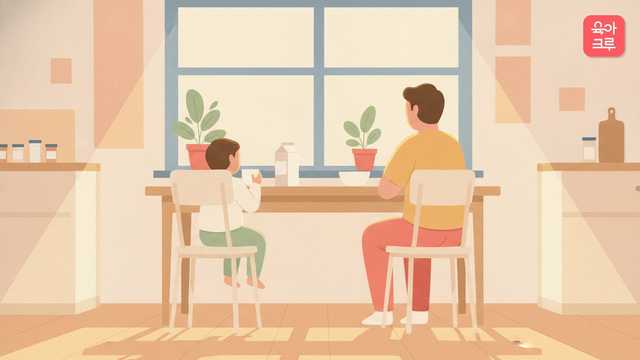 부엌 식탁에서 두 살 아이가 두 손으로 컵을 들고 우유를 마시는 뒷모습 그림