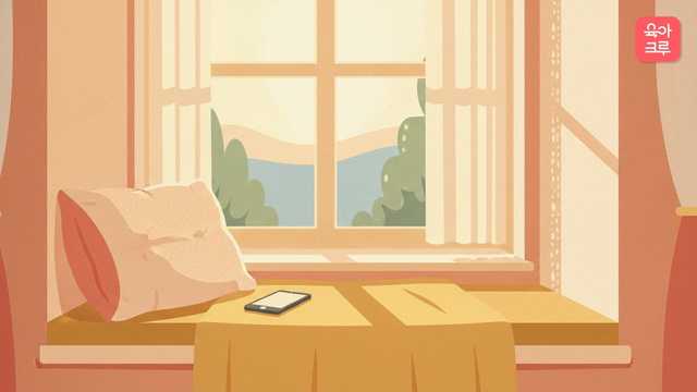 창가에 앉아 휴대폰을 보는 모습